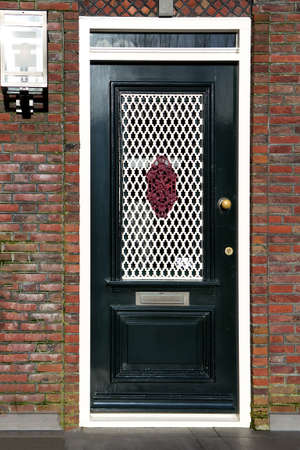 Beautiful black entrance door with glass panels and wrought-iron burglar grillsの写真素材
