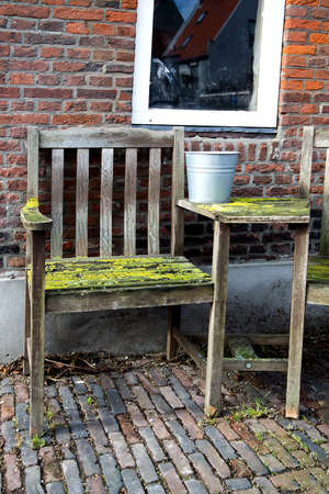 Outdoor view of a wooden old chair and table covered with mossの写真素材