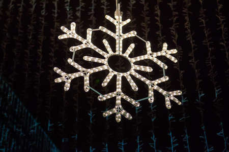 Christmas garland in the shape of a beautiful snowflake, decorates the city and shines brightly at night. Selective Focus.の写真素材