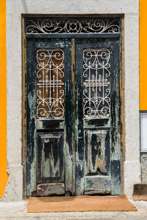 Vintage wooden doors with metal lattice built in stone house. Ancient Portugal building with old rusted doorの写真素材