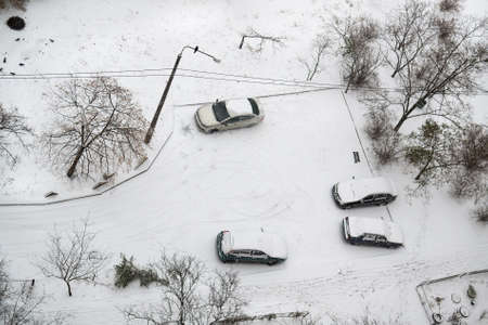 View from above to the yard of residential building after snowfall with snow covered cars. Selective focusの写真素材