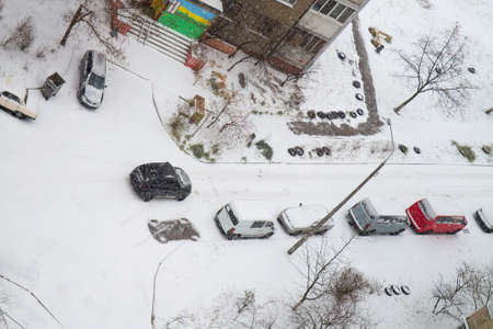 View from above to the yard of residential building after snowfall with snow covered cars. Selective focusの写真素材
