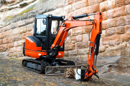 Small machine res excavator on sidewalk during repair works on street in urban environmentの写真素材