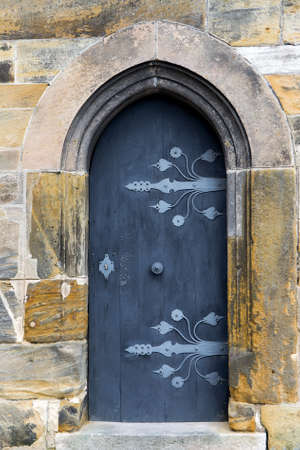 Arched wooden door with handmade handle and with forged metal patternの写真素材