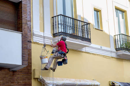 Worker paints building wall, renovating worksの写真素材