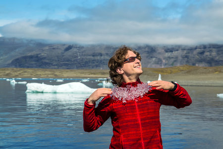 Man in sunglasses trying on ice decoration. Vatnajokull National Park, Iceland. Selective focus
