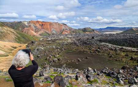 Adult woman with a tablet pc in a mountains. Selective focusの写真素材