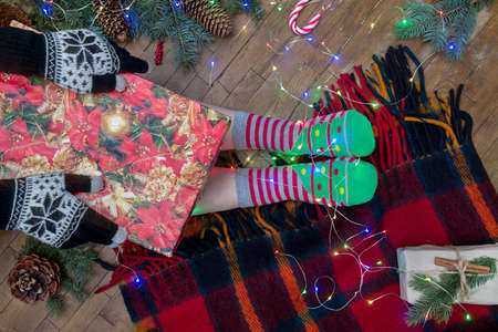 Christmas celebration at home, crossed female feet in socks and New Year giftの写真素材