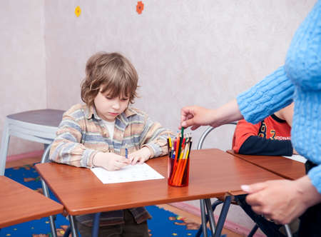 Boy sitting at the table, writing homework or preparing for the exam, home education. Selective focusの写真素材