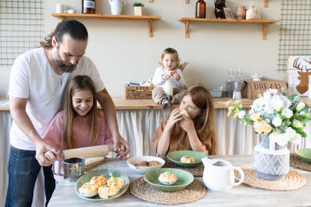 A family with three children has fun baking together.Dad And Daughter Laughing And Cooking Healthy Food Front View Lifestyle Concept . Candidの写真素材