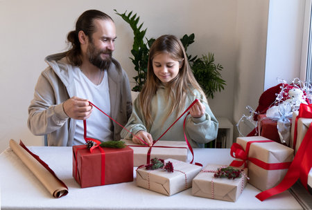 Merry Christmas and Happy Holidays. Cheerful dad and daughter are packing eco gifts for the whole...