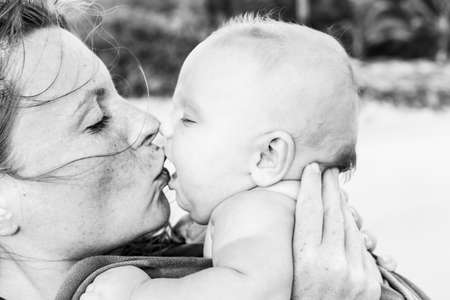 Mom kisses the newborn baby. Black and white close-up portrait on the beach . High quality black and white photoの写真素材