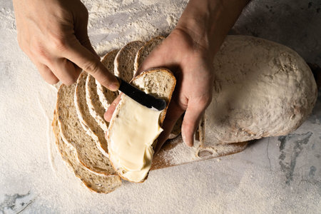 Man spreading cream cheese butter or a slice of bread slice on wood board. Dieting bread. Close-up....