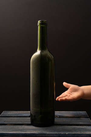 The concept of the wine bottle and hand template. A postcard for your design and product advertising on a black background with a copy space. A mock-up of a wine bottle. Front viewの写真素材