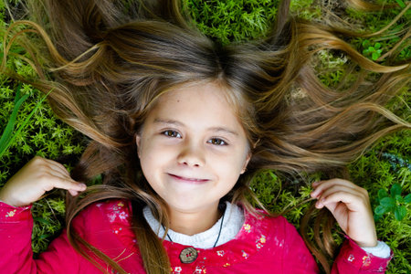 outdoor lifestyle portrait of a young happy and beautiful girl of caucasian European origin, relaxing in a city park, relaxed,の写真素材