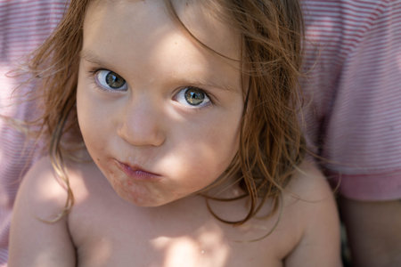 Portrait of a cute baby. The kid eats a watermelon and looks at the camera . Lifestyle. Candid. The concept of an active family holiday. Front view. Close-up.の写真素材