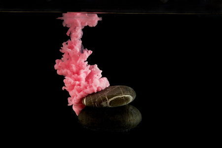 Pink acrylic paint in black water.Black background, perfect layout for your design. . A podium made of natural stone for your cosmetic product or jewelry.の写真素材