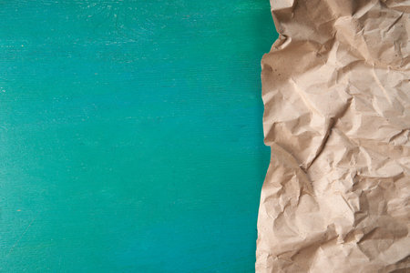 Half of crumpled eco-friendly packaging paper on a green wooden background. An excellent blank for your text or your design. Copy Space. The concept of ecology, recycling, zero waste.の写真素材