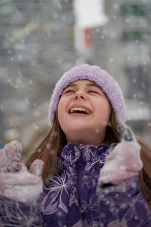 A young beautiful teenage girl laughing . Snow flakes are falling ,the girl is happy about winter and the upcoming New Year holidays.Front view, concept of holidays and winter festivalsの写真素材