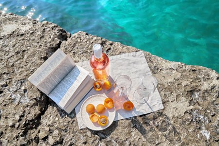 Two glasses of wine and summer fruits on the beach, sea and landscape in the background, summer picnic, travel, vacation, weekend getaway outdoorsの写真素材