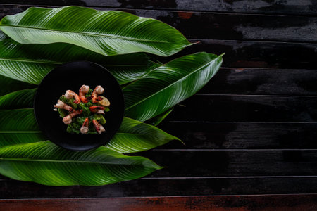 Grilled tiger shrimp arranged beautifully on a black plate, surrounded by lush banana leaves, reflecting the rich culinary heritage of Asia. A feast for the senses awaits.の写真素材