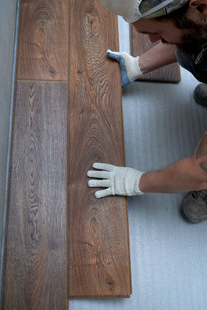 Mens gloved hands lay laminate flooring. view from above. the concept of repair and renovation.の写真素材