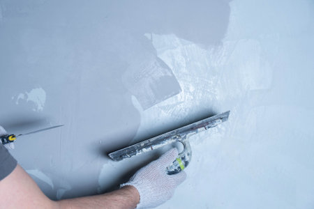 Technician uses a trowel to apply epoxy adhesive for surface repair in a workshop.の写真素材