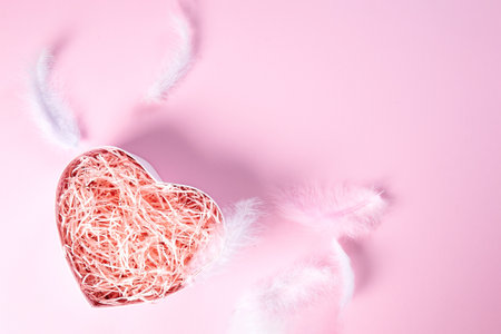 Heart-shaped gift box on a pink background with feathers . Layout for your product.High angle. Holidays, romance, Valentines Day, Cosmetic products, perfume,の写真素材