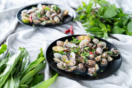 Plates of clams and mussels with garlic and vibrant green herbs ready for a seafood feast.の写真素材