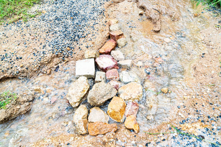 Water weaves through stones, creating a natural pathway amidst greenery in a serene landscape.