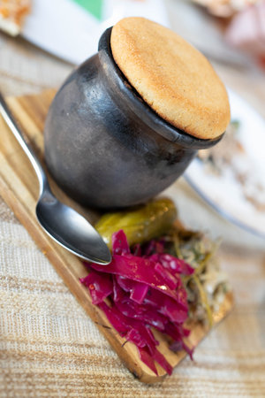 Gathered around the table, a family enjoys a lavish dinner featuring a rustic pot of delicious food...