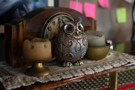 A beautifully arranged display in a vintage interior features an ornate owl figurine alongside candles and a rustic clock. This inviting scene highlights the warmth of family gatherings and memories.の写真素材