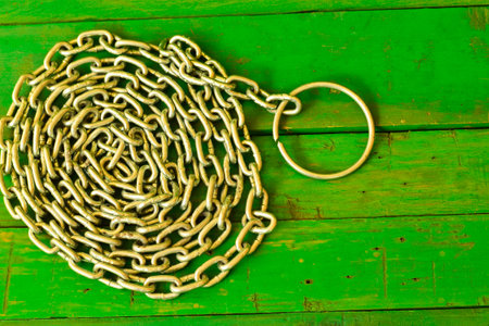 Close up old metal chain on green wooden background