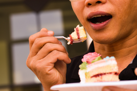 Man eating a piece of cake, close up mouth eatingの写真素材
