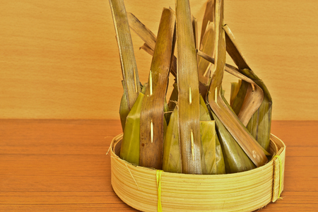 Thai dessert wrapped with banana leaves and coconut leaves on bamboo basketの写真素材