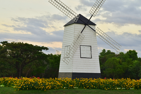 Turbine wooden house with flower garden and light of sunset in cloudy blue sky.の写真素材