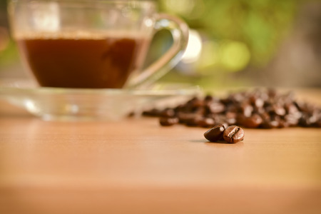 scattered roasted coffee beans on wooden table and a cup of coffee backgroundの写真素材