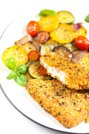 Fried tilapia fish fillet with vegetables on white plate の写真素材