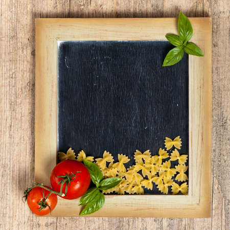 Italian Food. Pasta, Tomatoes, Basil on black chalkboard. Selective focusの写真素材