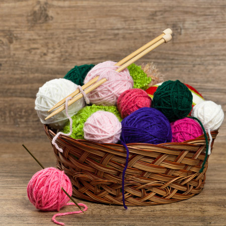 Balls of yarn in a basket with knitting needles. Selective focus.