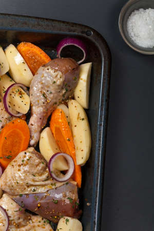 Raw chicken thighs on frying pan with potato. Selective focus.の写真素材