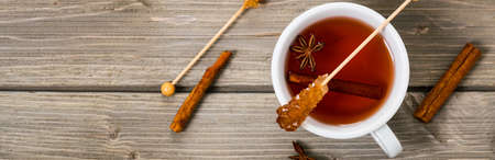 Cup of Hot Spicy Tea with Cinnamon, Anise and Honey on a Wooden Background, Top View. Panoramic image. Selective focus.の写真素材