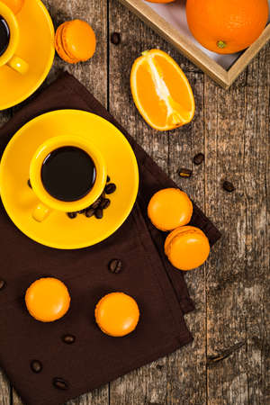 Orange French Macarons with Coffee Beans on Wooden Table Top view. Selective focus.の写真素材