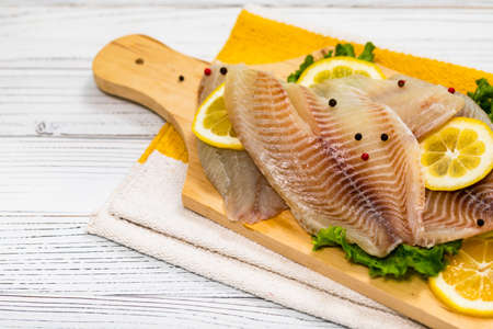 Whitefish Tilapia Fish Raw Fillet on White Wooden Background. Selective focus.の写真素材