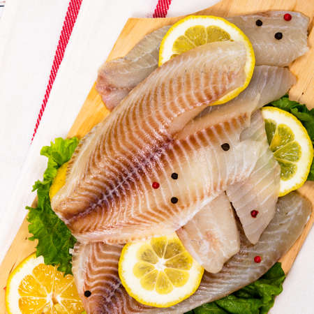 Whitefish Tilapia Fish Raw Fillet on White Wooden Background. Selective focus.の写真素材