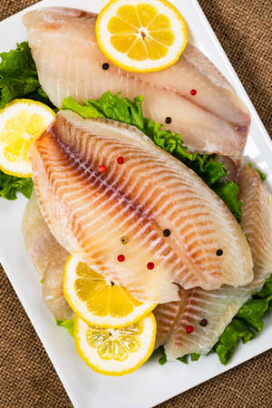Whitefish Tilapia Fish Raw Fillet on Wooden Background. Selective focus.の写真素材
