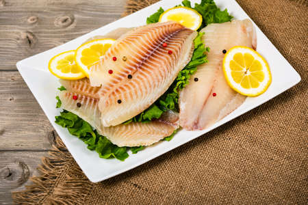 Whitefish Tilapia Fish Raw Fillet on Wooden Background. Selective focus.の写真素材