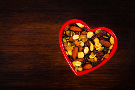 Energy Blend Trail Mix with Nuts and Dried Fruits in Heart Shaped Bowl. Selective focus.の写真素材