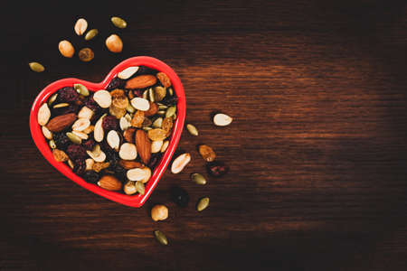Energy Blend Trail Mix with Nuts and Dried Fruits in Heart Shaped Bowl. Toned image. Selective focus.の写真素材