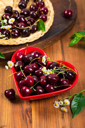 Cherries in Heart Shaped Bowl on Wooden Background. Selective focus.の写真素材